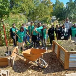 student volunteers posing by raised flower beds