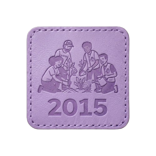 Light purple square patch with stitched border. Features a silhouette of a group of people planting in a garden and the text "2015."